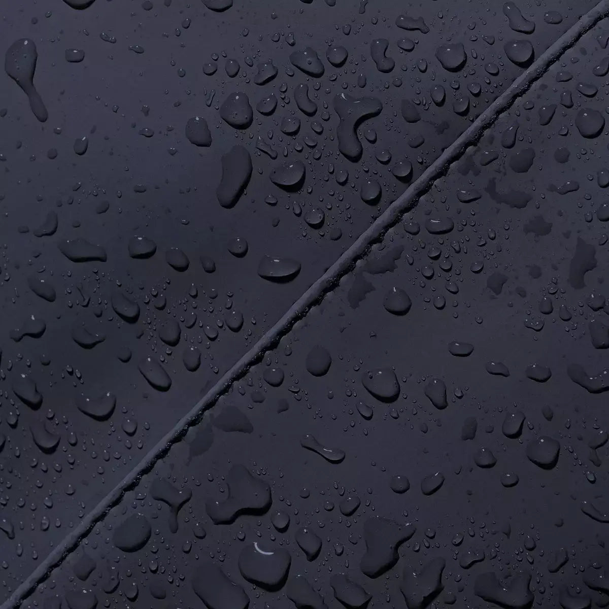 Waterproof material detail of the Masao Lotus Dark Navy Backpack showing water droplets and durability.