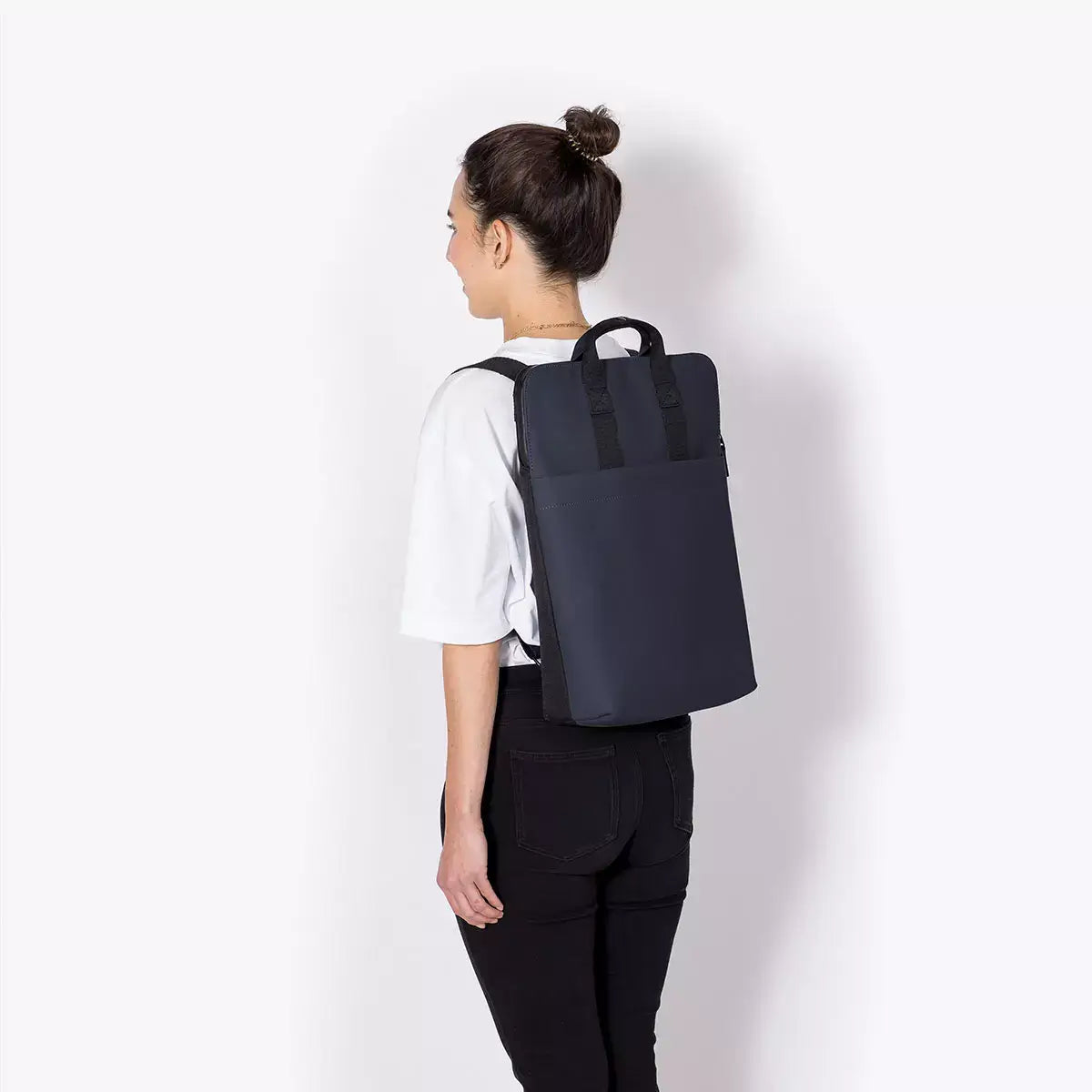 Person wearing the Masao Lotus Dark Navy Backpack, showcasing its sleek design and functionality.
