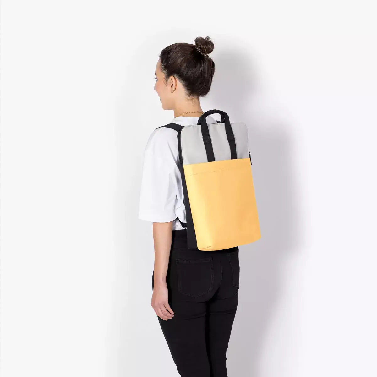 Masao Lotus Infinity Glacier Grey Lemon Backpack worn by a person from behind, showcasing its unique colors and design.