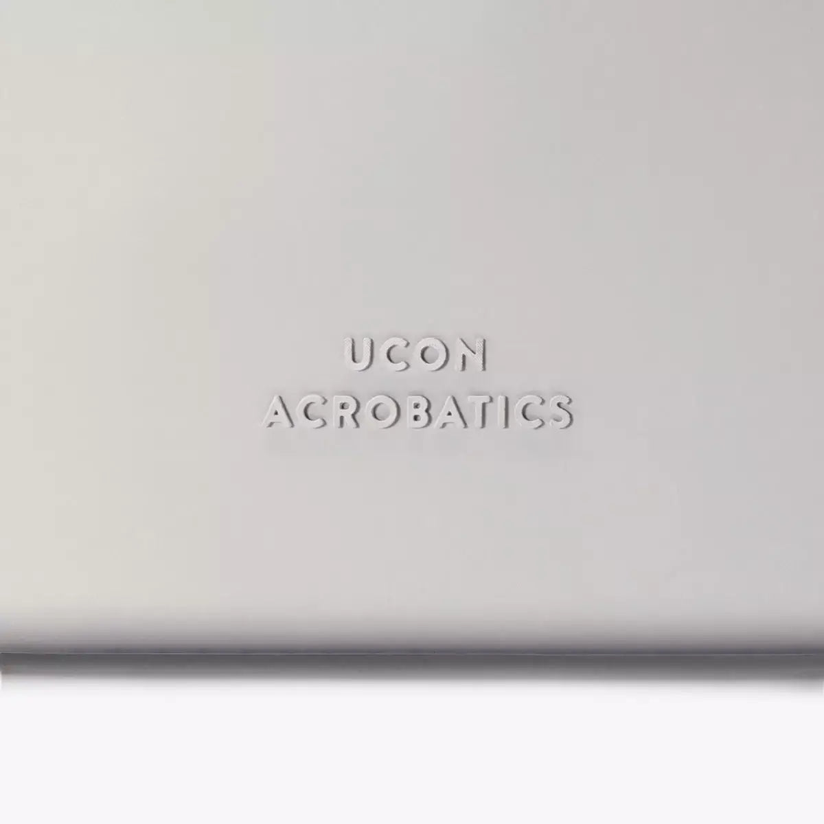 Ucon Acrobatics logo embossed on a light grey background.