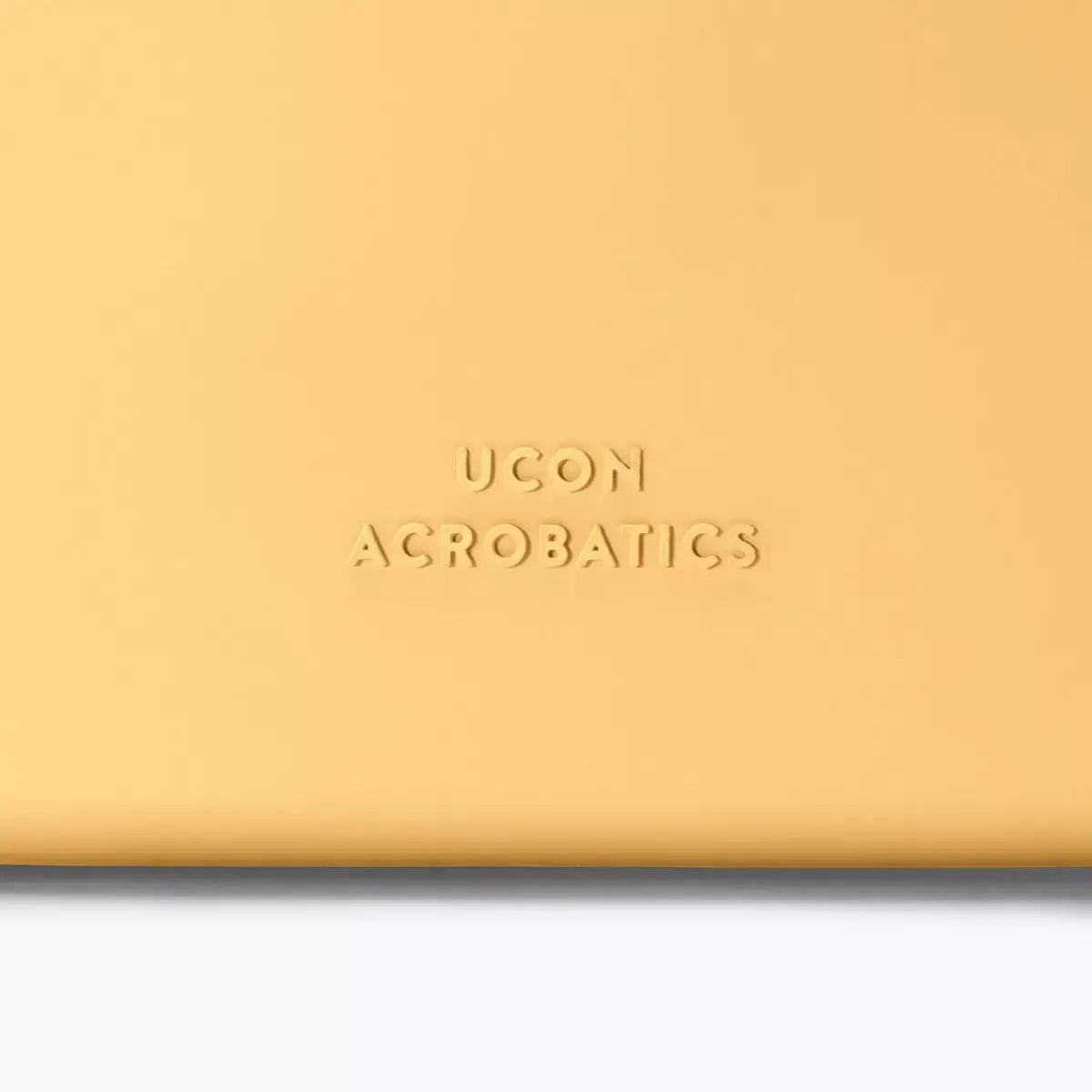 Close-up of UCON ACROBATICS branding on a yellow bag, showcasing the embossed logo.