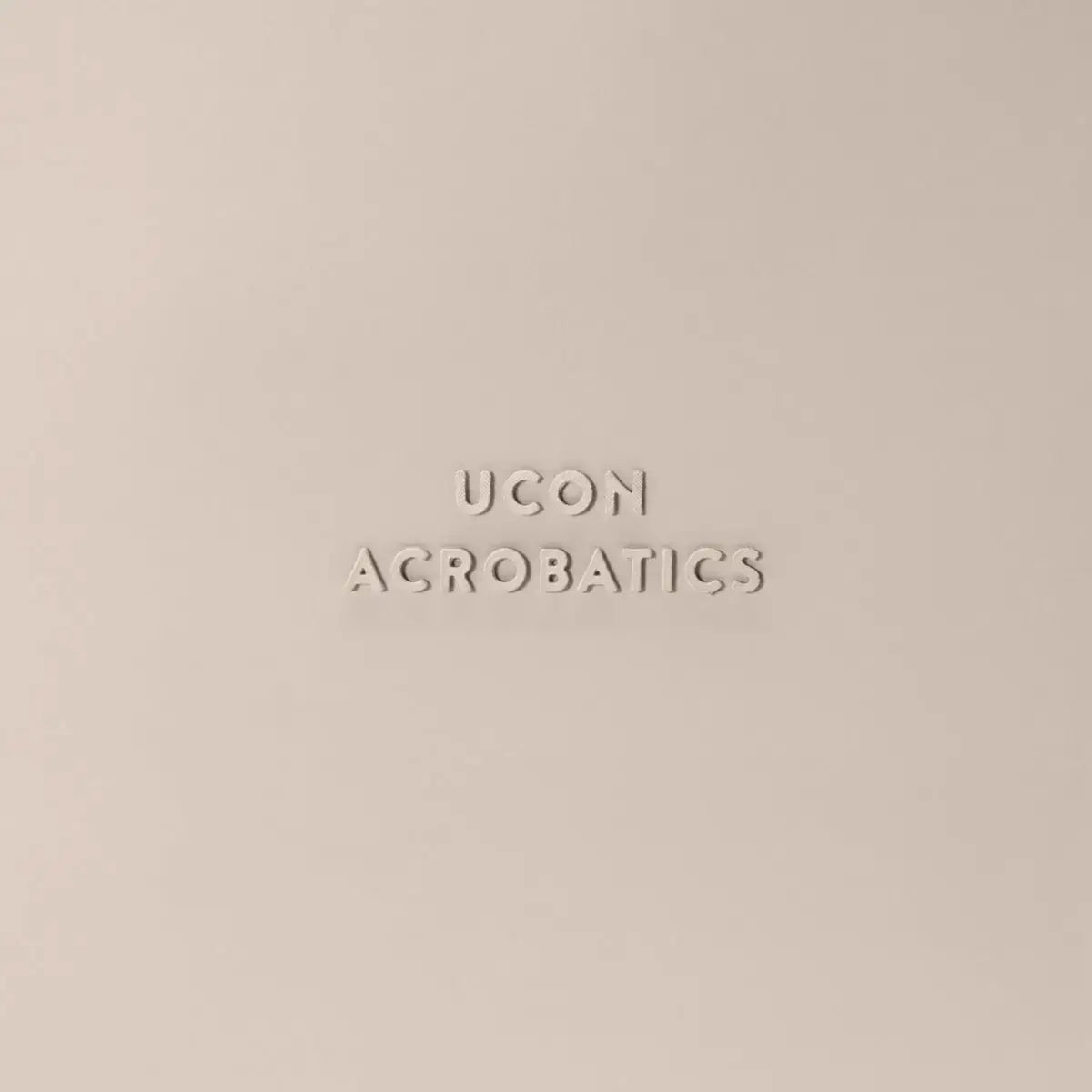 Ucon Acrobatics logo embossed on a beige background, representing stylish and modern design.