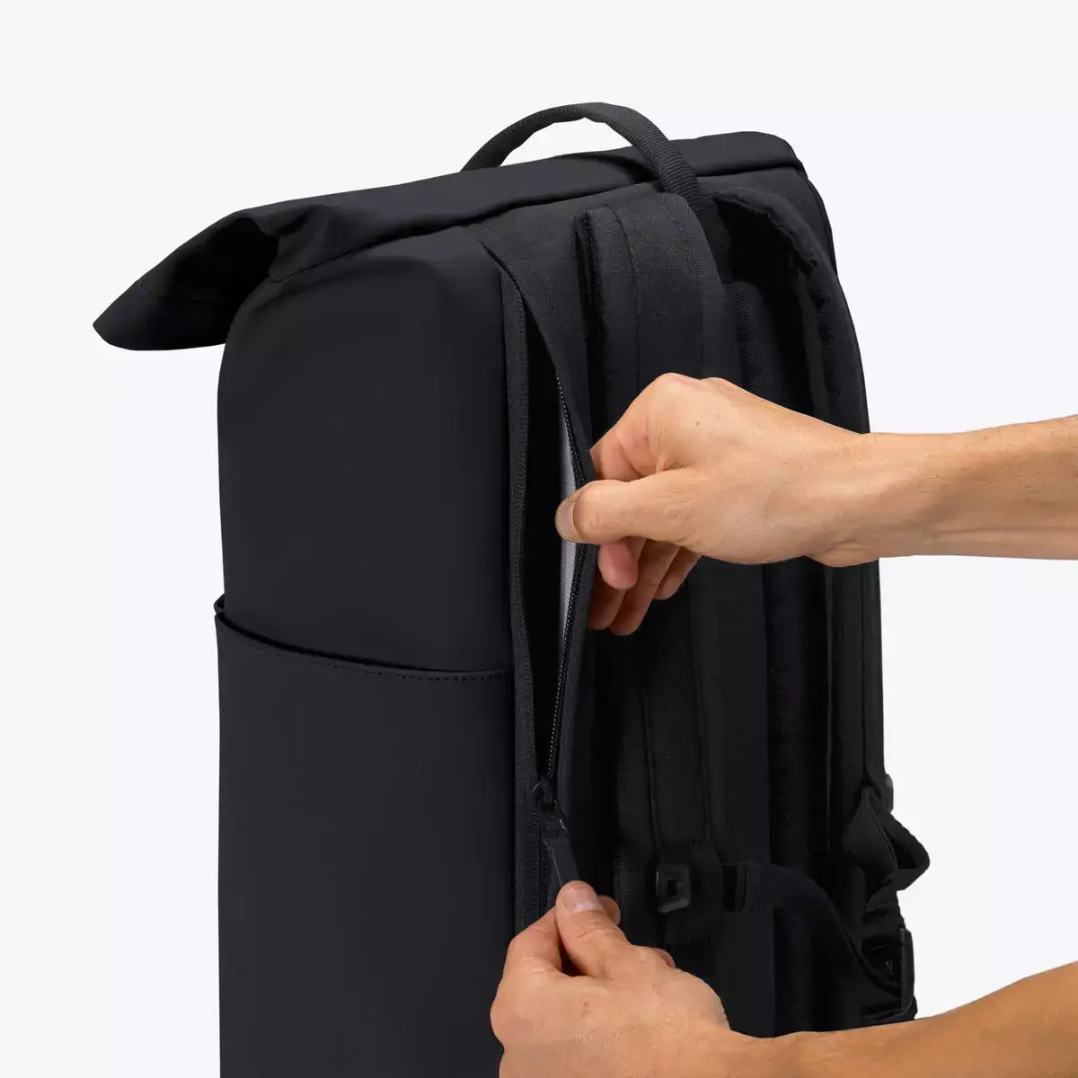 Person adjusting the straps on the Yuto Medium Lotus Infinity Black Backpack, showcasing its sleek design.
