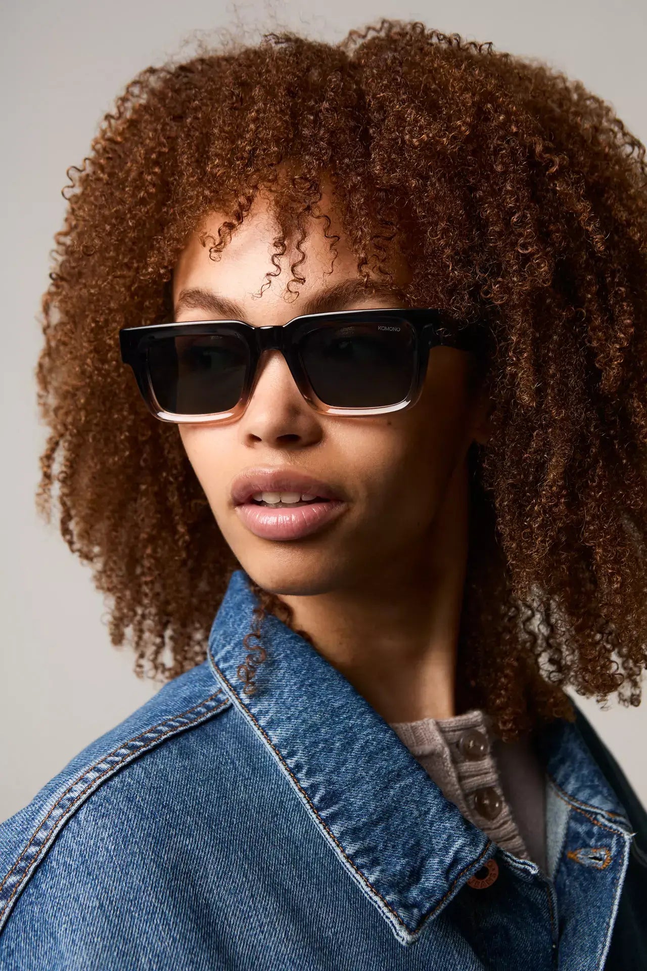 Model wearing Victor Atlantic Sunset Sunglasses with curly hair and denim jacket against a neutral background.
