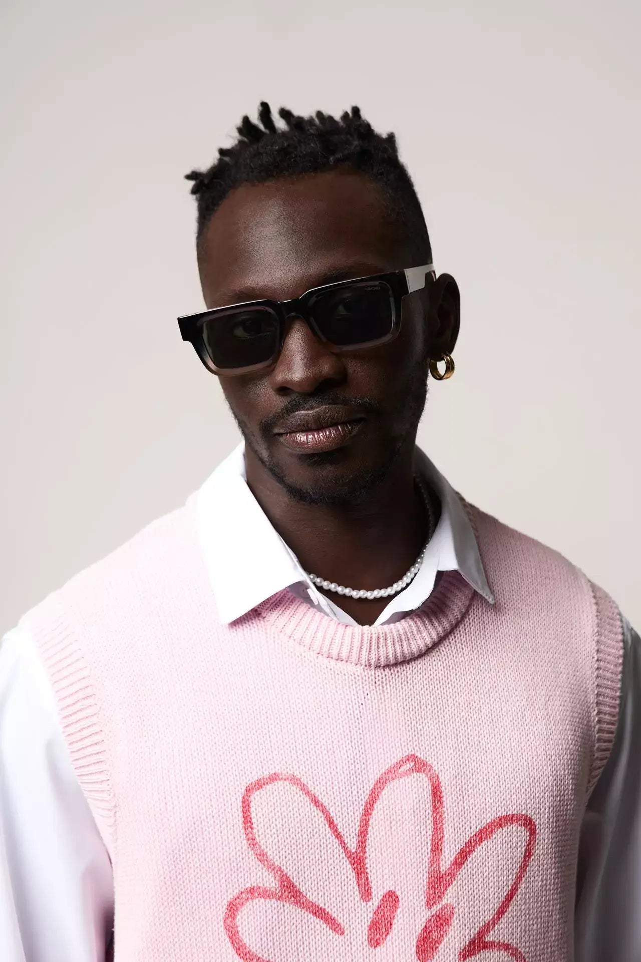 Man wearing Victor Atlantic Sunset Sunglasses with pink vest and stylish accessories.