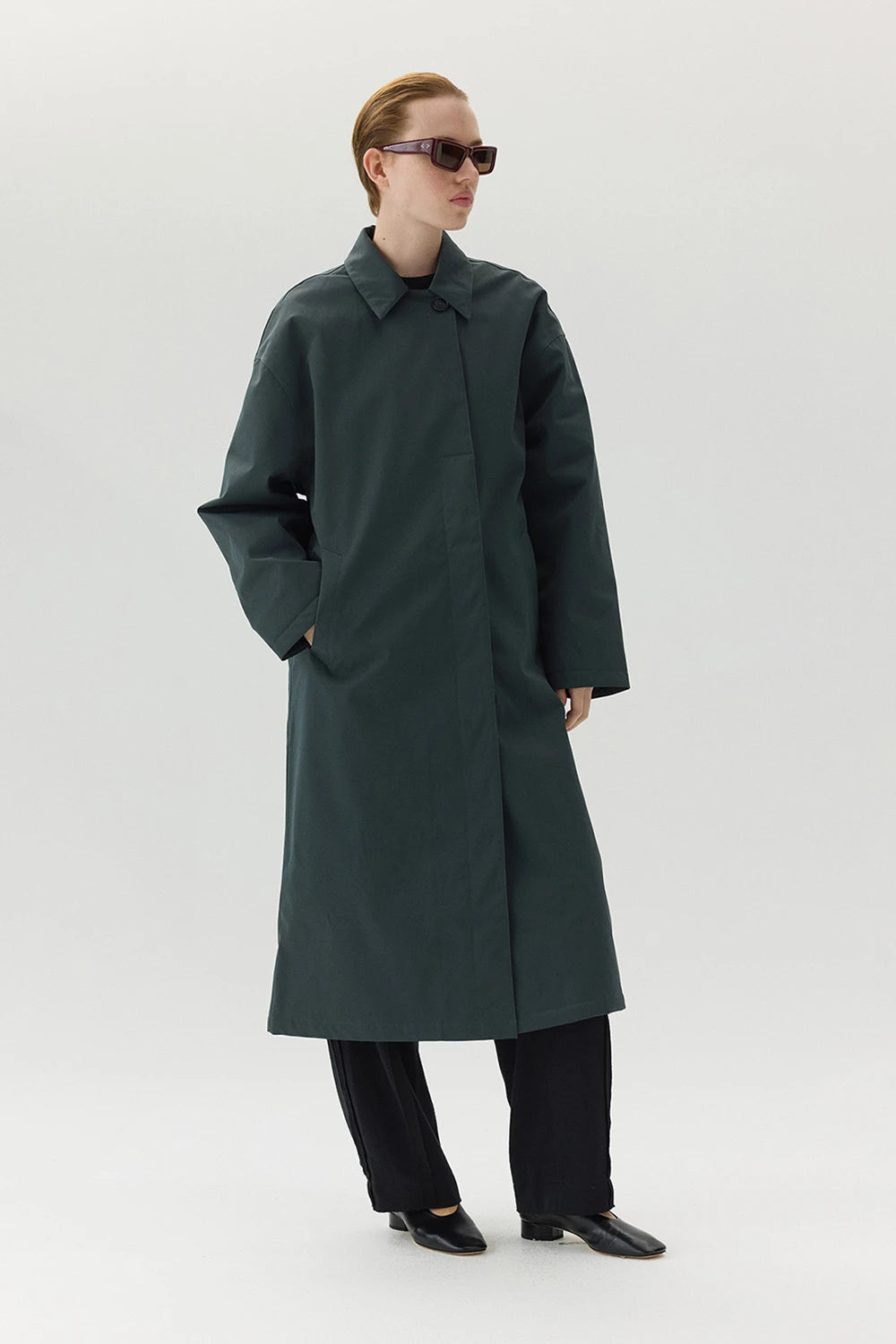Model wearing the Janice B Ninspin Forest Green Coat in a casual fit with sunglasses.