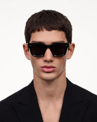 Model wearing 04 Core Black Sunglasses with anti-scratch lenses and durable Acetate Renew™ material.
