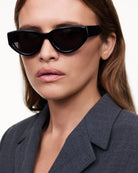 Model wearing 06 Core Black Sunglasses with a stylish outfit, showcasing modern eyewear design.