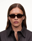Model wearing 10 Core Brown Sunglasses with stylish black outfit, showcasing sleek design and perfect fit.