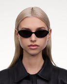 Ellipse Black Sunglasses worn by a model with long hair, featuring a stylish black frame and sleek design.