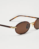 Lea Royal Tortoise Sunglasses with brown lenses and gold detailing on a neutral background.