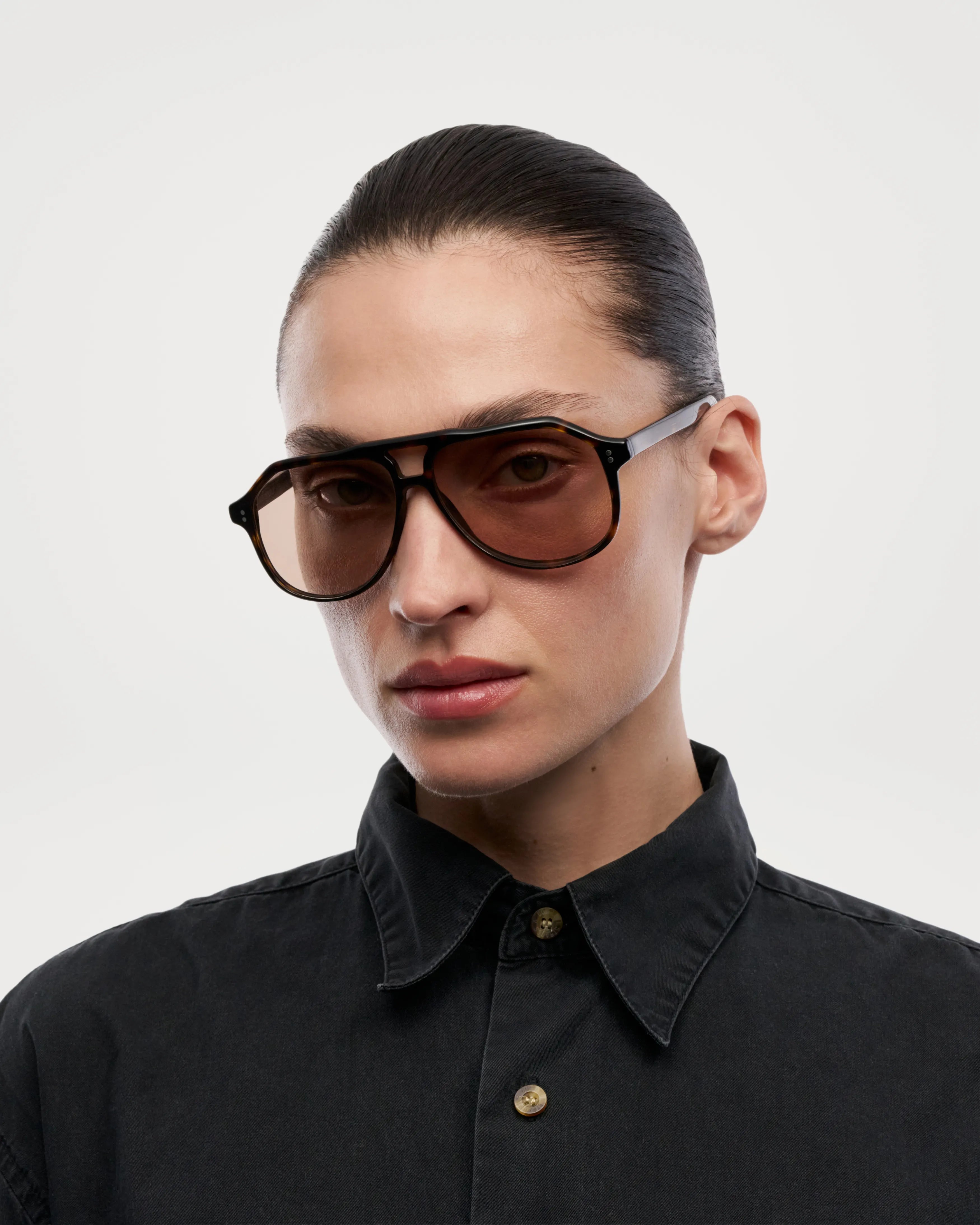Sally Terra Tortoise Sunglasses worn by a model with sleek hair and black shirt against a minimalist background.
