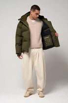 Model wearing Bayu Dark Olive Green Coat with a sweater and pants showcasing its interior features.