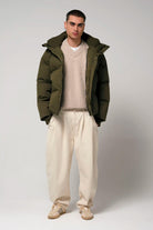 Model wearing Bayu Dark Olive Green Coat over a beige sweater and cream pants, showcasing a stylish winter outfit.