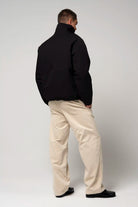 Man wearing Claud Deep Black Coat from the back, paired with beige pants and black shoes.