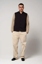 Model wearing a Claud Deep Black Coat with beige sleeves, paired with light-colored trousers and black shoes.