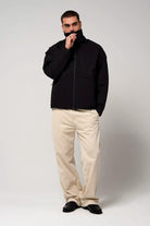 Man wearing Claud Deep Black Coat with a high collar, black jacket paired with light beige pants.