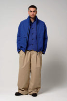 Model wearing the Claud Sodalite Blue Coat paired with relaxed beige pants, showcasing a stylish and functional look.