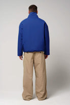 Back view of a man wearing the Claud Sodalite Blue Coat with beige pants.