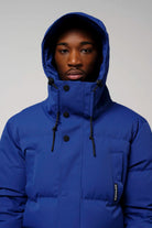 Model wearing the Climate Sodalite Blue Coat with hood, showcasing its vibrant blue color and design.