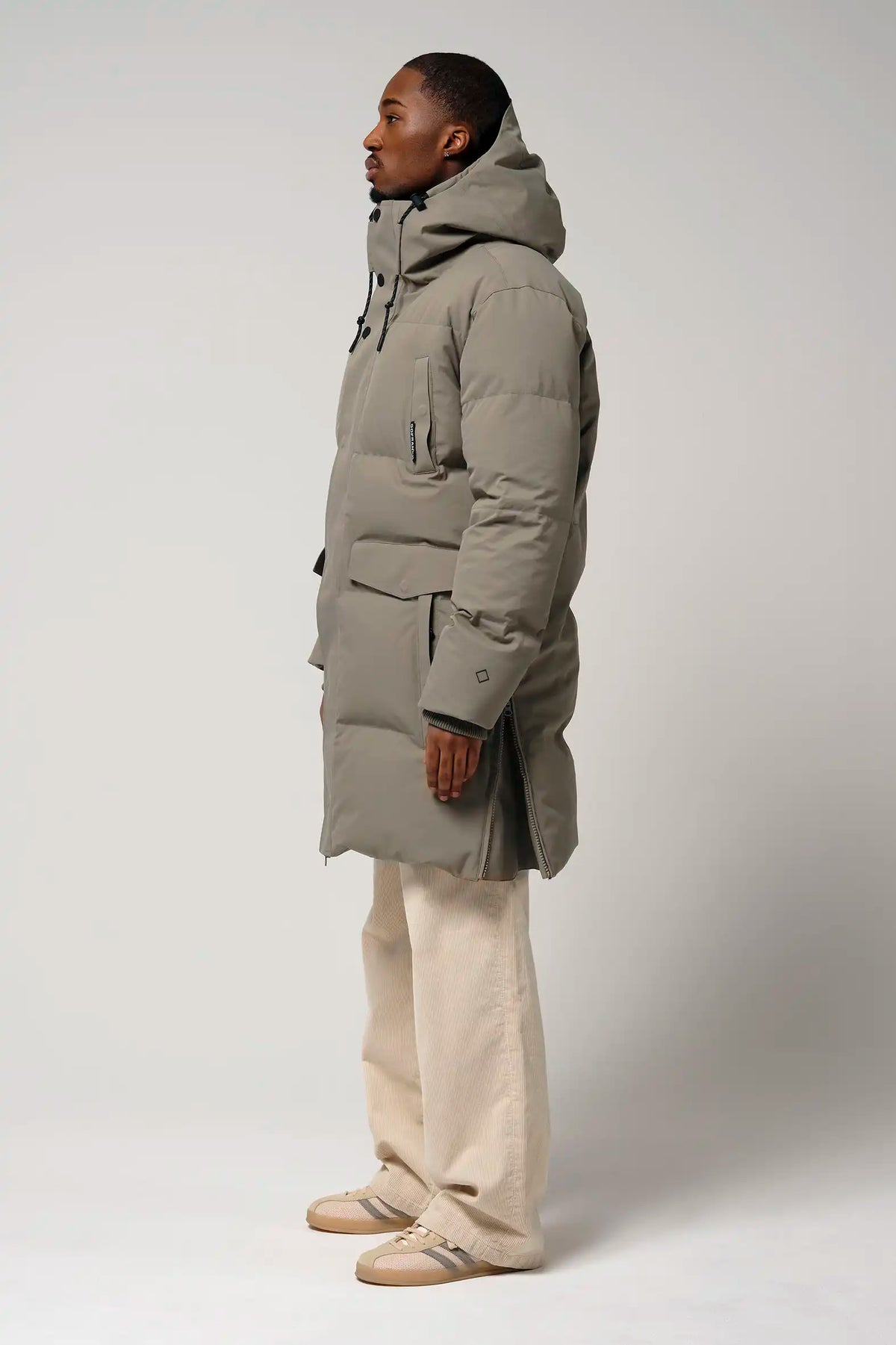Climate Timber Wolf Grey Coat side view on model wearing beige pants and shoes, showcasing its modern design and functionality.