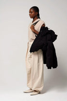 Model wearing a light outfit holding the Guthrie Deep Black Coat, showcasing its stylish design.