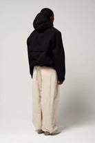 Model wearing Guthrie Deep Black Coat from the back with adjustable hood and loose-fitting pants.