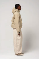 Guthrie Fields of Rye Beige Coat shown on a model, featuring an adjustable hood and two outer pockets.