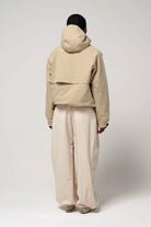 Back view of a person wearing the Guthrie Fields of Rye Beige Coat with adjustable hood and relaxed fit pants.