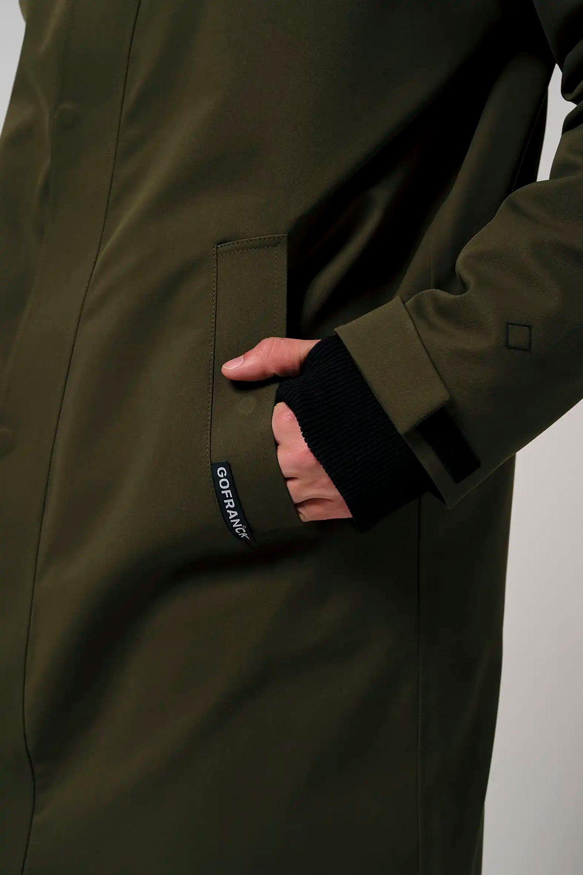 Person wearing the Raiden Dark Olive Green Parka, showcasing the pocket and cuff design.