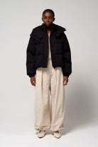 Model wearing Talon Deep Black Coat with stylish beige pants, showcasing modern urban outerwear.