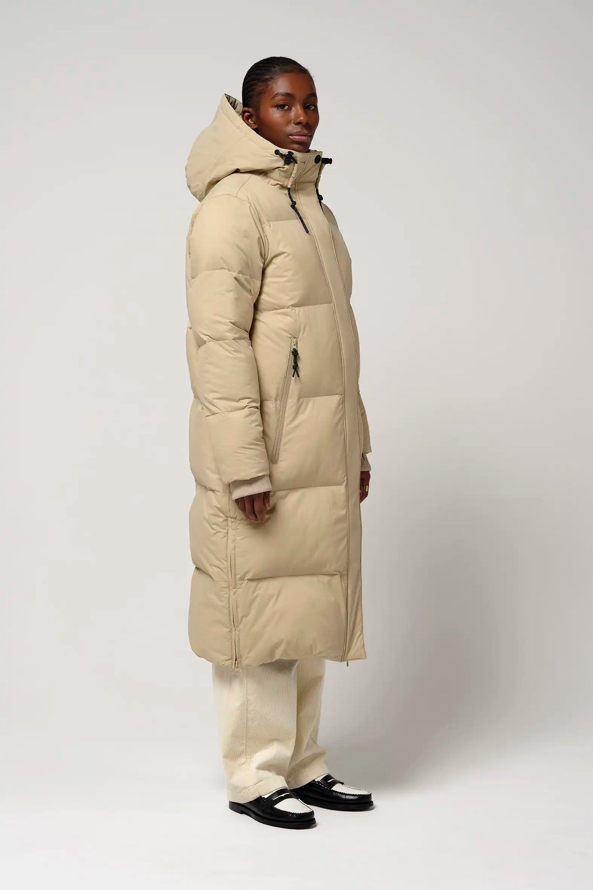 Model wearing Tsunami Fields of Rye Beige Coat, a lightweight waterproof puffer coat in beige.