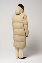 Model showing the back view of the Tsunami Fields of Rye Beige Coat, a lightweight waterproof puffer coat.