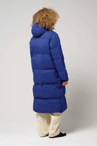 Tsunami Sodalite Blue Coat shown from the back on a model with curly hair, highlighting its long design and vibrant blue color.