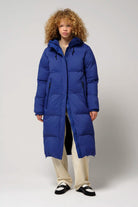 Model wearing Tsunami Sodalite Blue Coat, a lightweight puffer, showcasing its waterproof and stylish design.