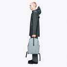 Clip Front Backpack Pool Backpack shown in gray, worn by model in waterproof attire, showcasing 29-liter capacity.