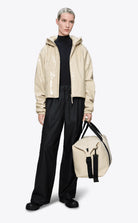 Model wearing Lohja Short Insulated Jacket Shore Coat paired with black pants and carrying a bag.