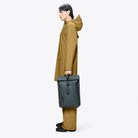 Person in a brown coat holding a fully waterproof Rolltop Rucksack Dark Grey Backpack.