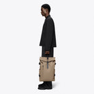 Rolltop Rucksack Large Beige Backpack being carried by a model in a black outfit, showcasing its stylish design.