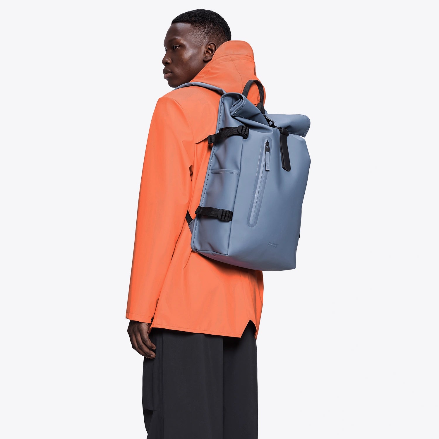 Rolltop Rucksack Large Blue Dusk Backpack worn on the back of a person in an orange jacket.
