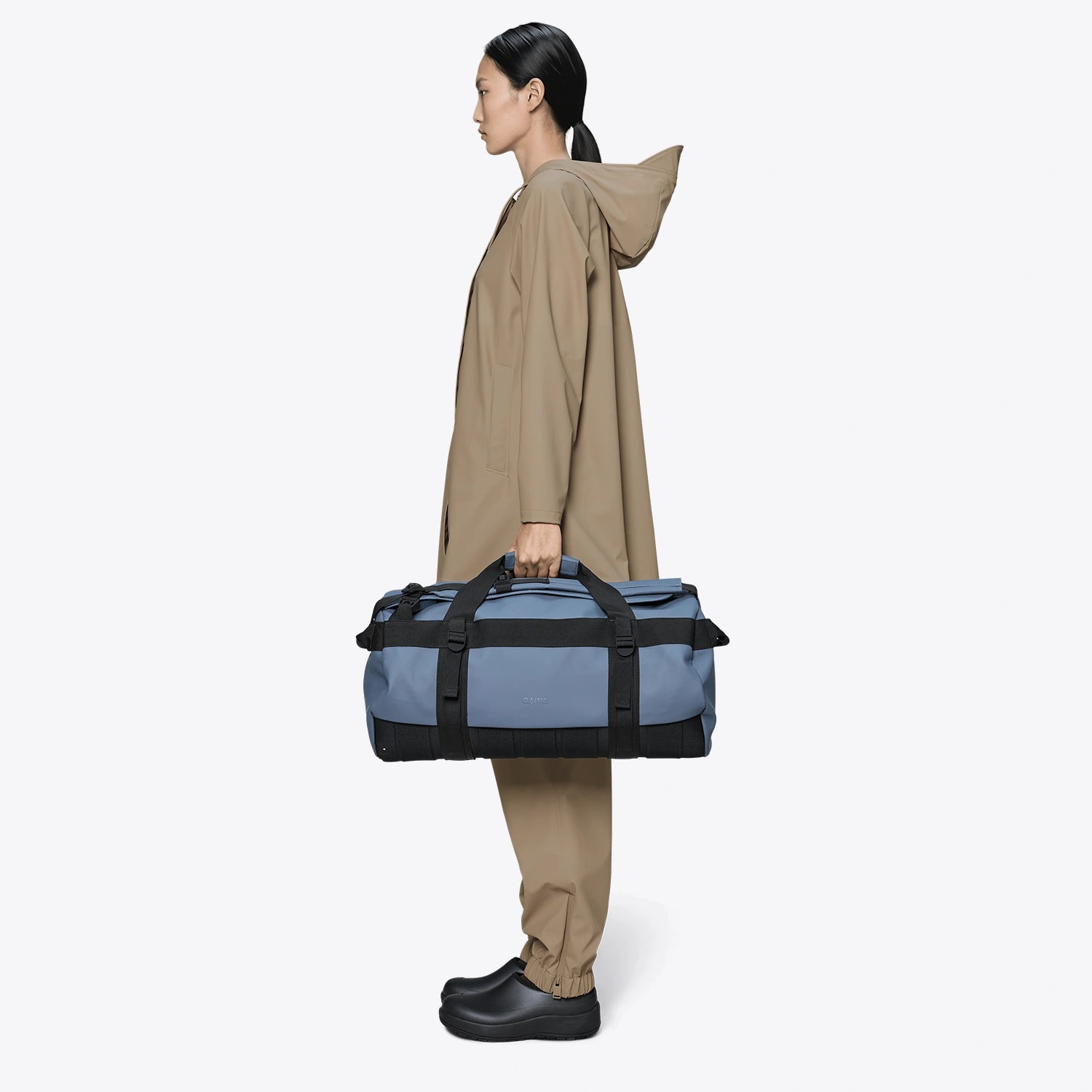 Texel Duffel Bag Small Blue Dusk Duffel Backpack being held by a person in waterproof gear.