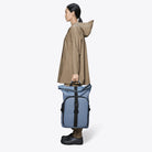 Texel Moulded Backpack Blue Dusk Backpack being carried by a person in a brown raincoat.