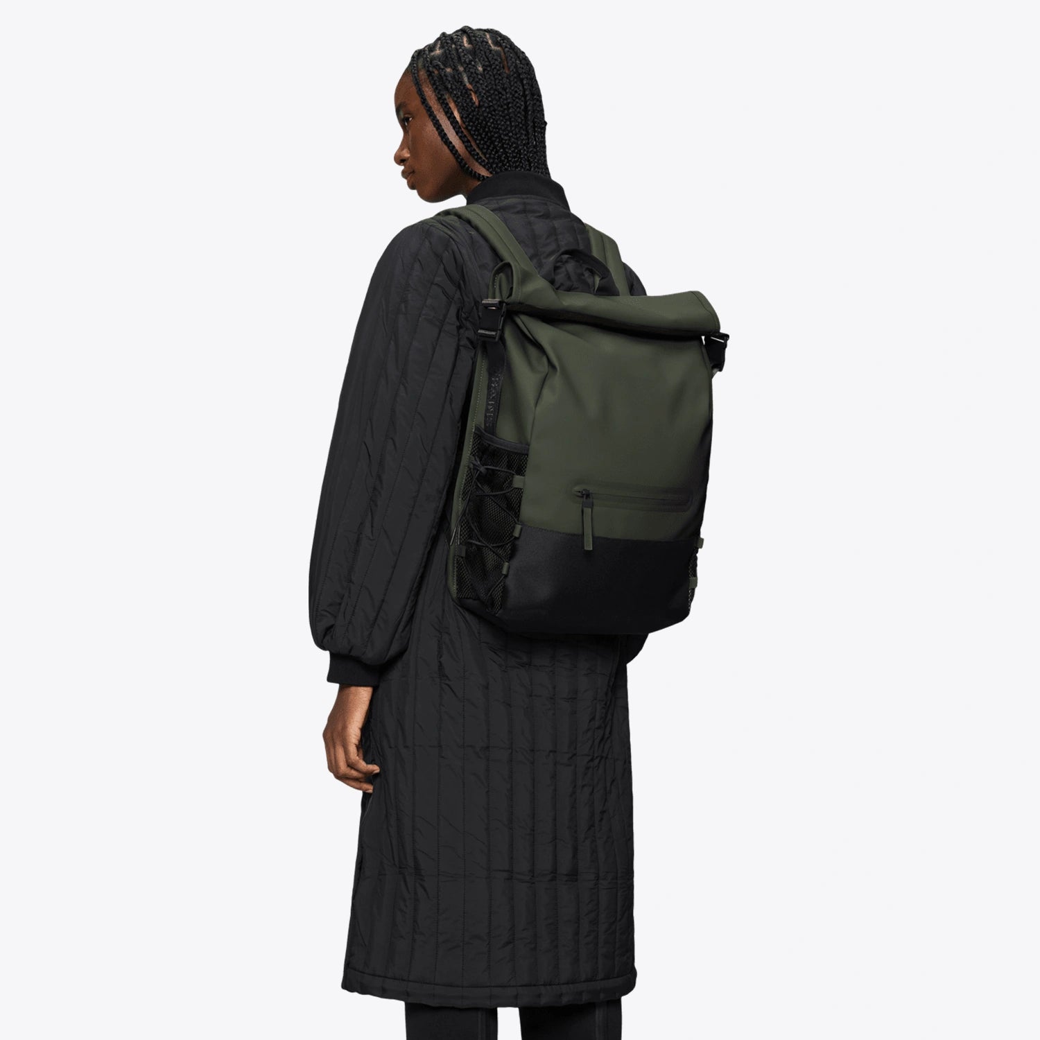 Woman wearing a Trail Mountaineer Rolltop Green Backpack, featuring roll-top closure and side pockets.