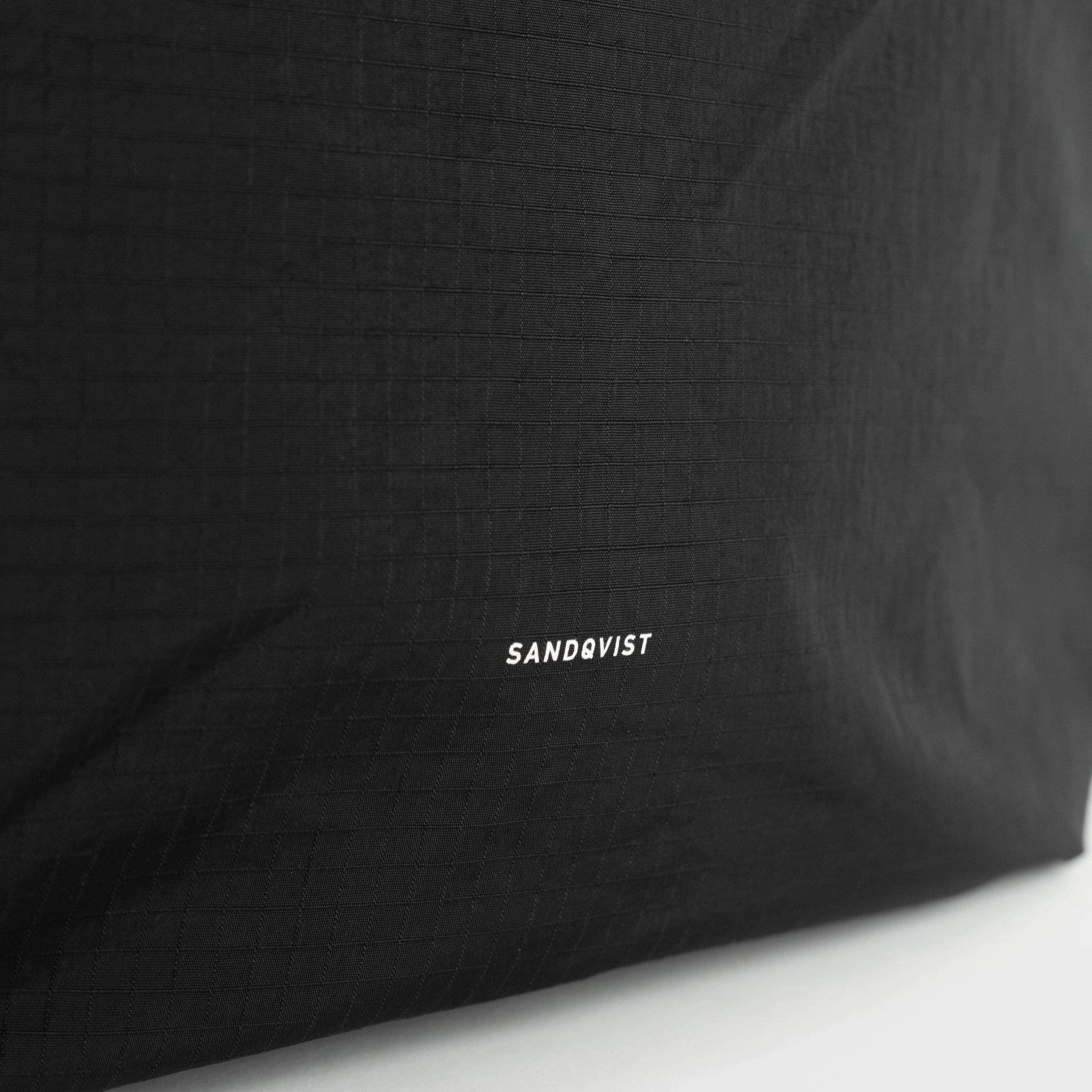 Grid Tote Bag Black Shoulder Bag featuring a close-up of the durable black fabric with SANDQVIST branding.