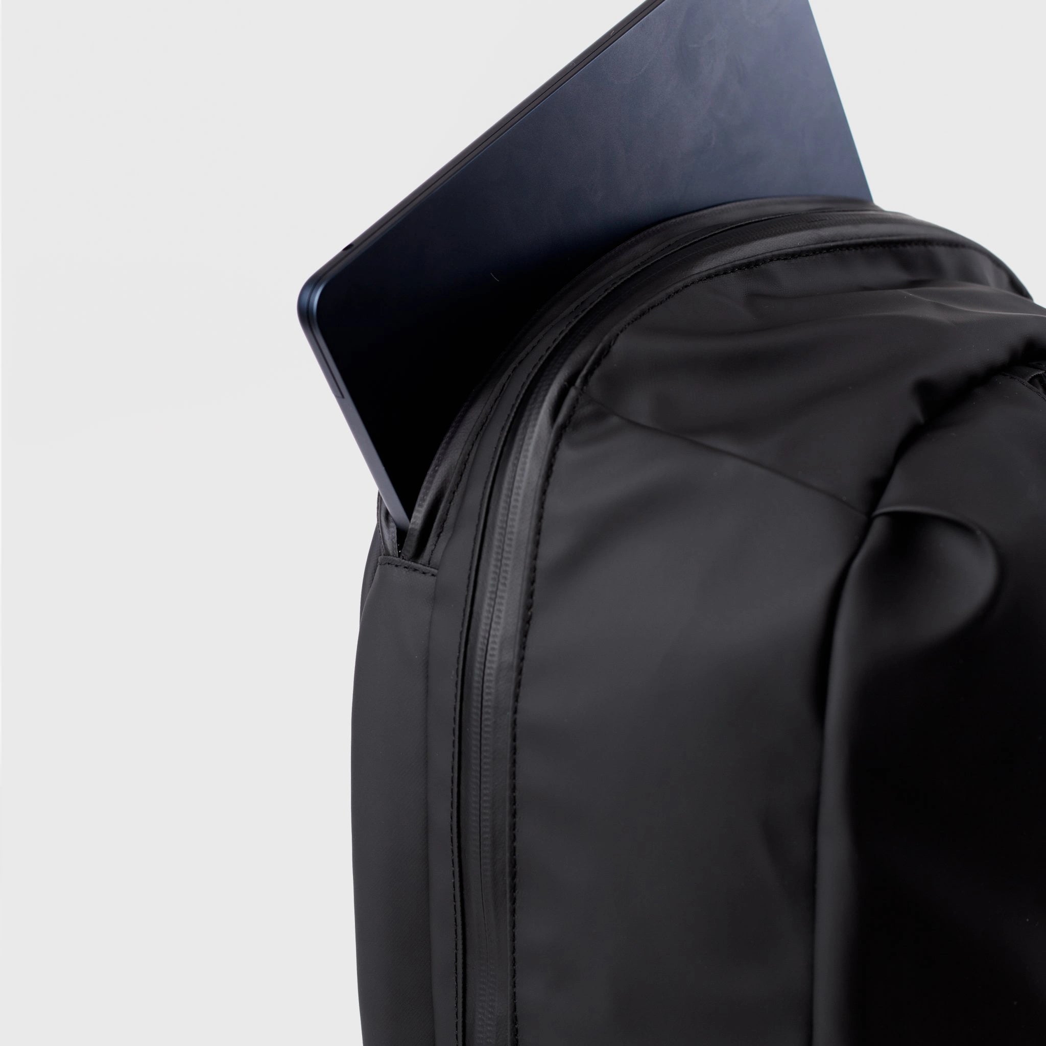 Stream Zipper Backpack Black Backpack with a laptop partially inserted into its padded compartment.