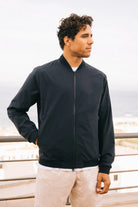 Model wearing Campo II Navy Jacket outdoors with a coastal backdrop, showcasing a lightweight, windproof design.