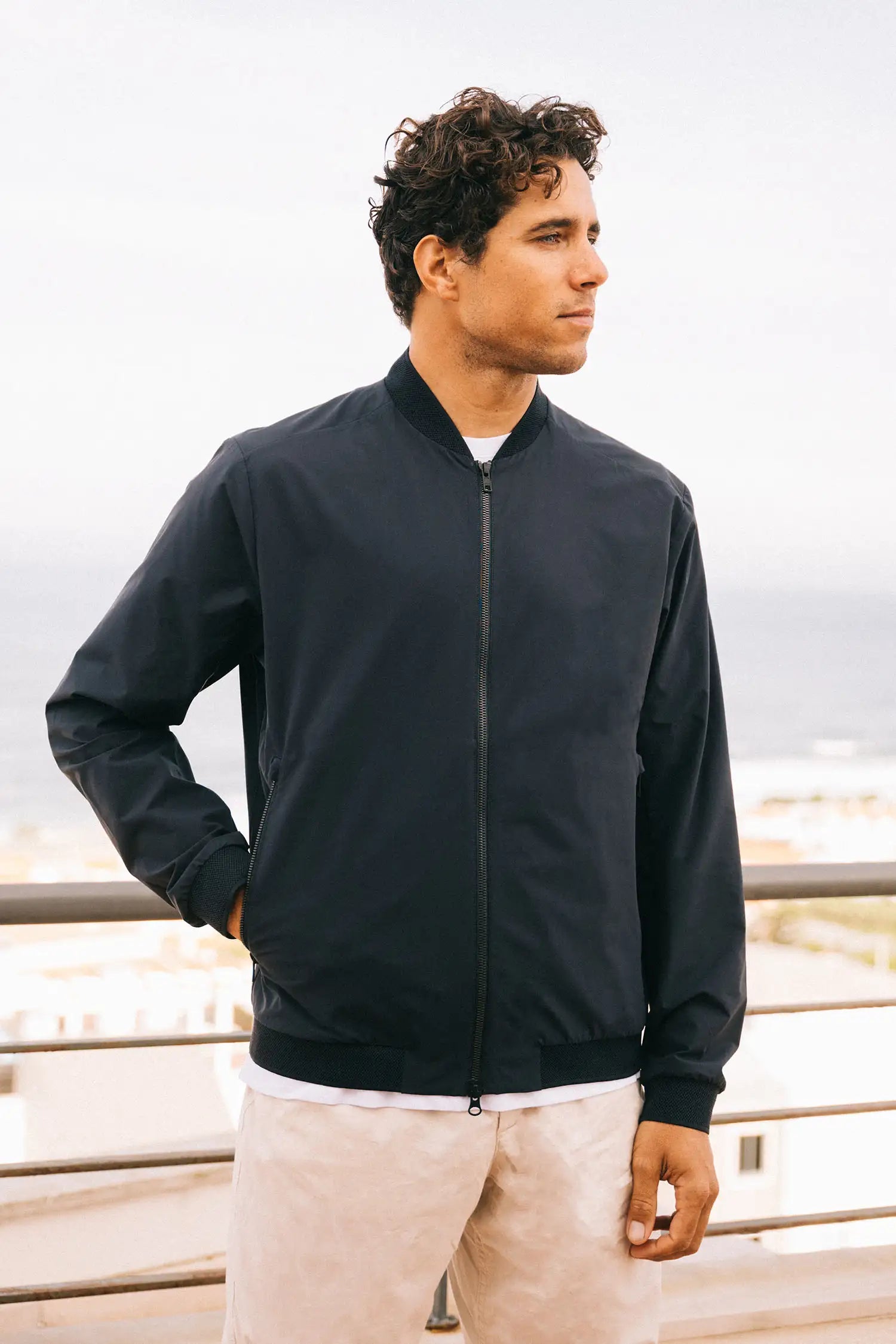 Model wearing Campo II Navy Jacket outdoors with a coastal backdrop, showcasing a lightweight, windproof design.