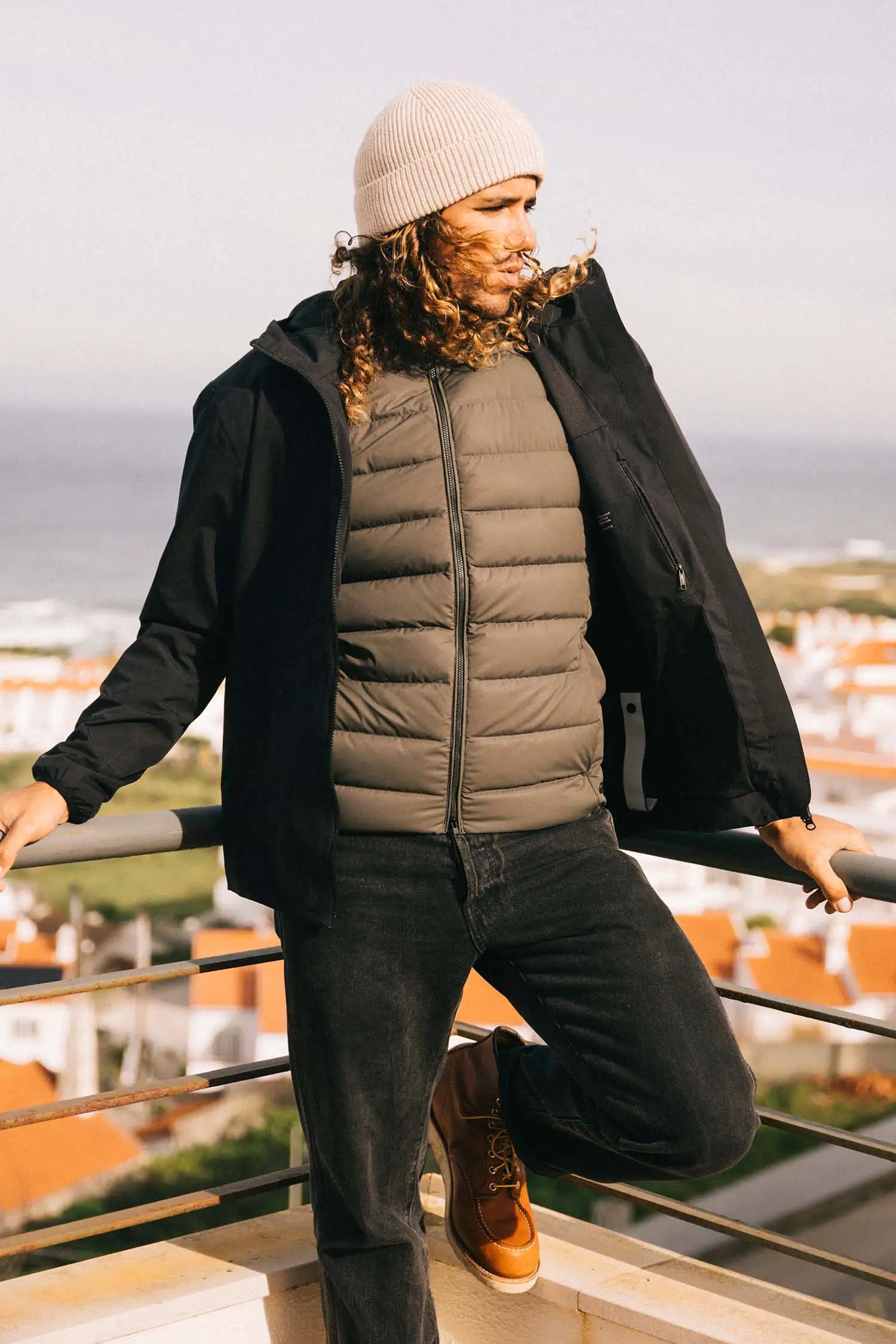 Man wearing Hood II Onyx Jacket and a knitted beanie, overlooking a scenic view.