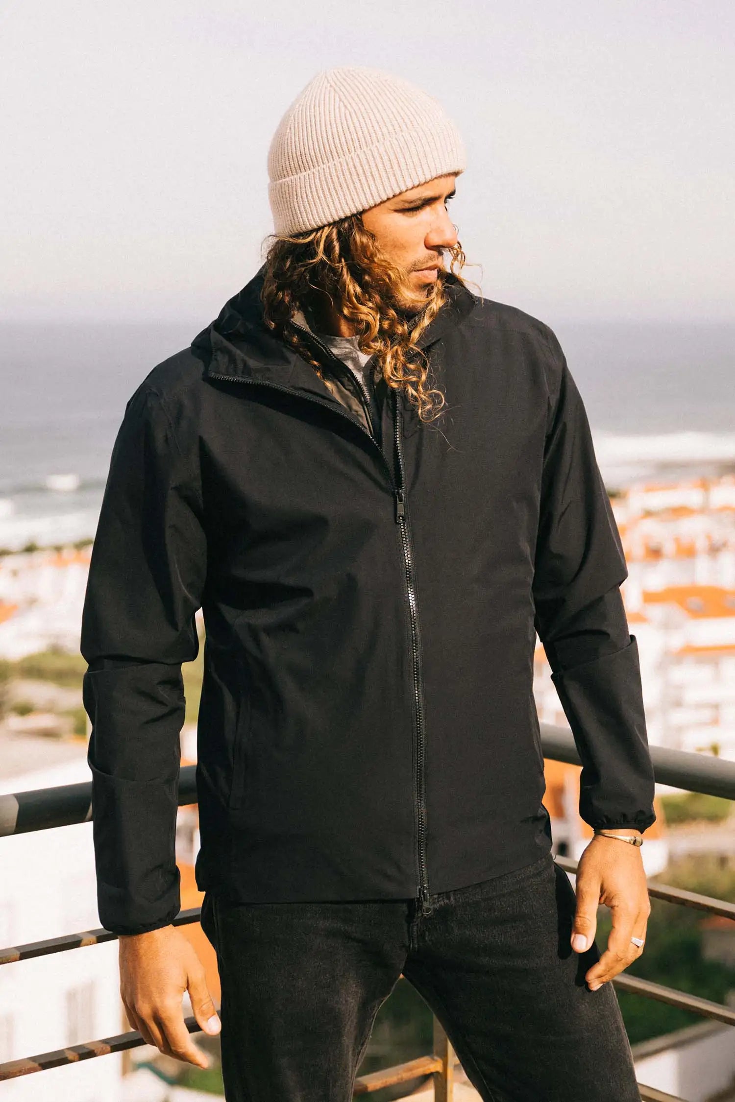 Man wearing Hood II Onyx Jacket against a scenic background, showcasing its lightweight and stylish design.