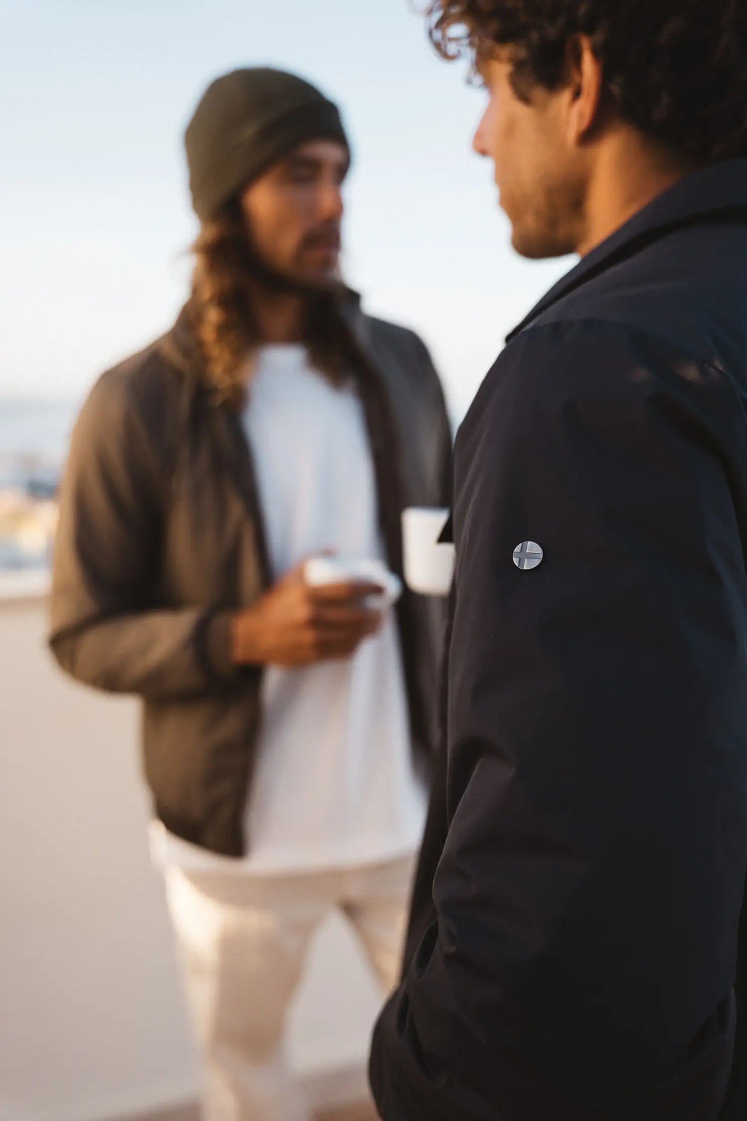 Two men outdoors wearing lightweight jackets, one model features the Trip II Graphite Overshirt close-up.
